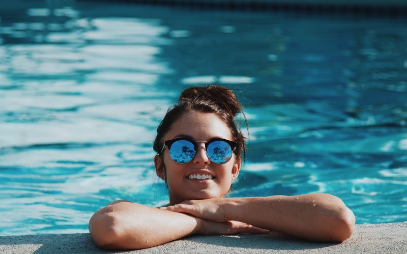 lifestyle image of a woman smiling on a pools edge